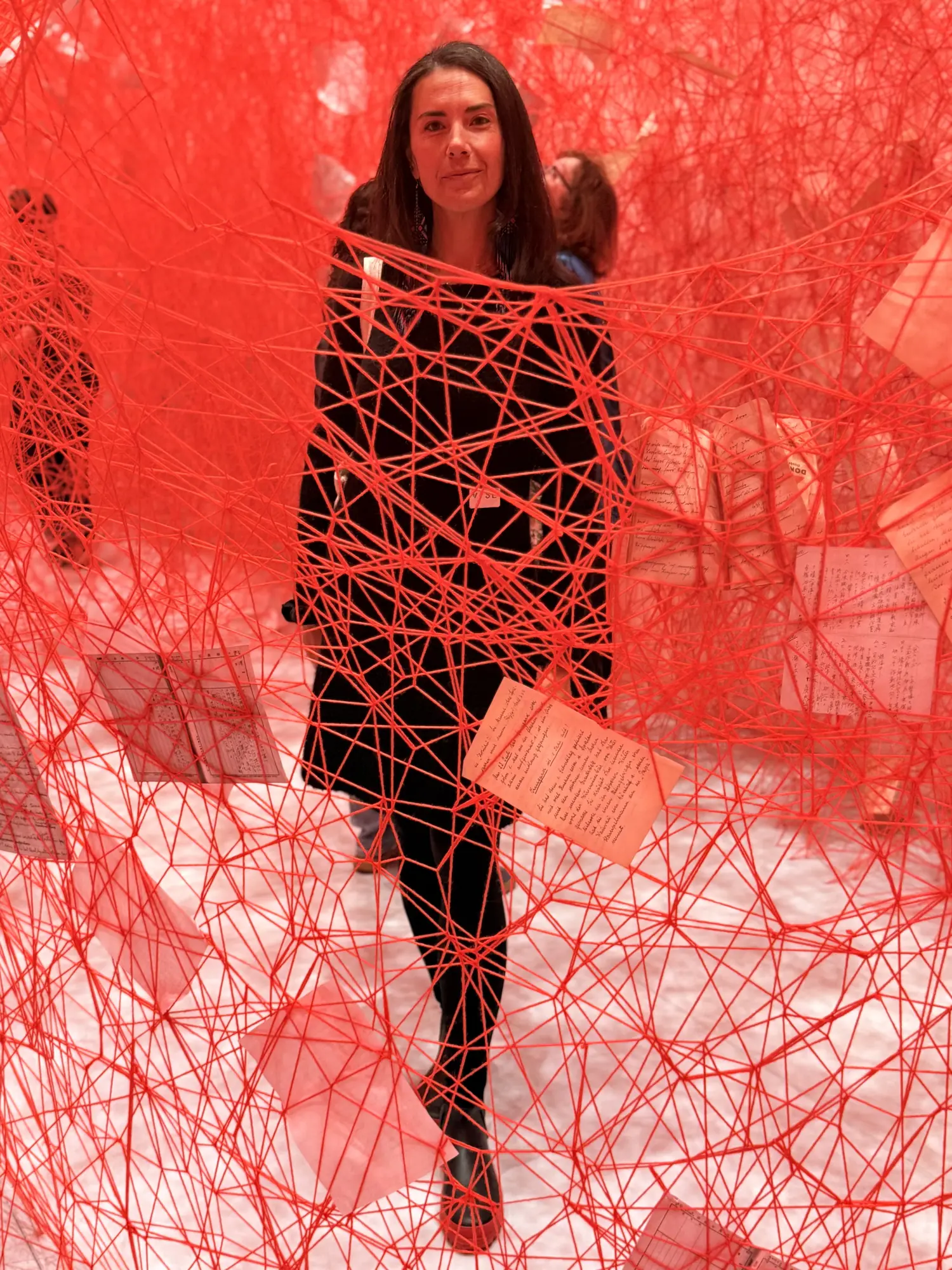 Sofia Ksendzovsky, standing inside a room woven with red thread.
